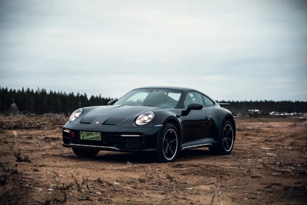 Black sports car on desolate landscape.