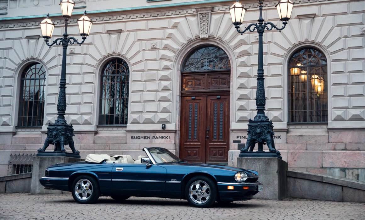 Vintage convertible car parked outside ornate historical building.