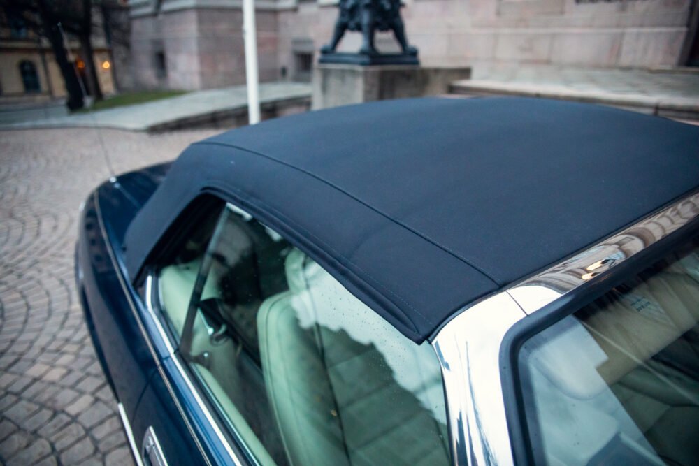 Close-up of black car roof and cobblestone background.