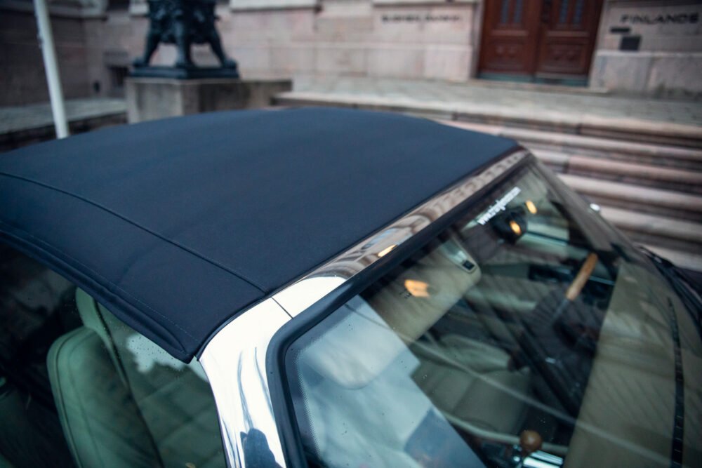 Close-up of convertible car roof near historic building.