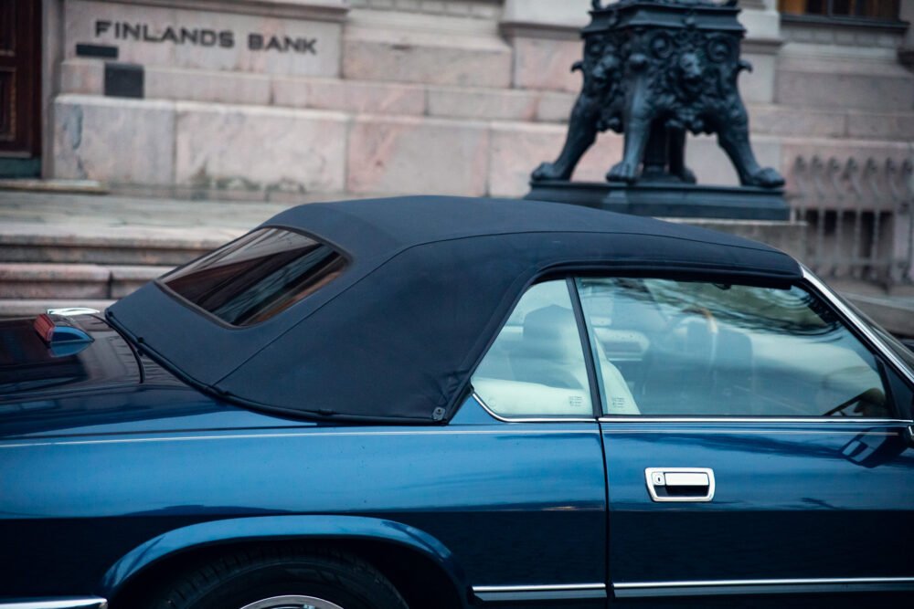 Blue car in front of Finland's Bank building.