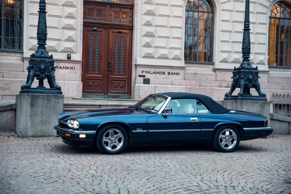 Vintage blue car parked outside Finland's Bank building.