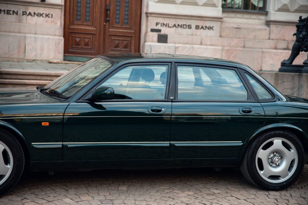 Dark green luxury car parked outside Finland's Bank.
