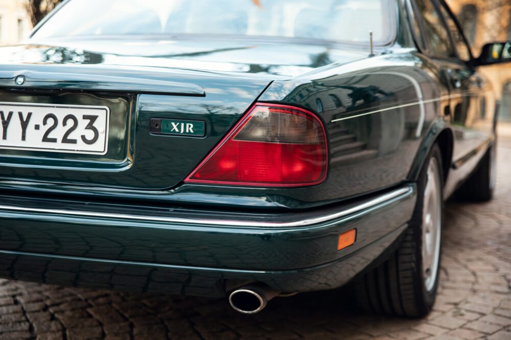 Green Jaguar XJR rear view showcasing tail lights and badge.