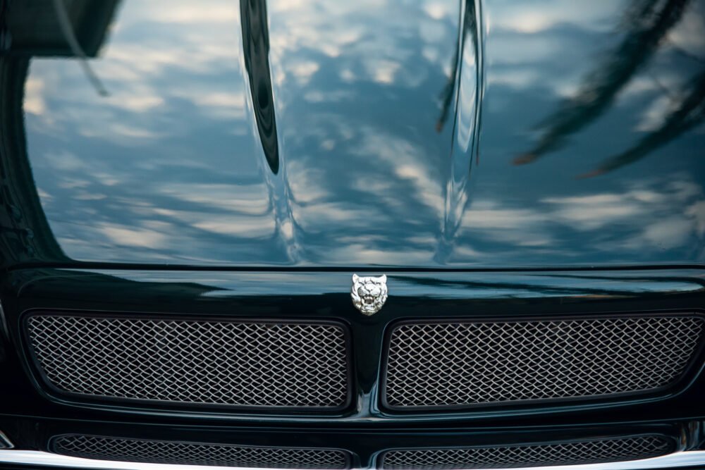 Black luxury car hood and emblem, reflective surface.