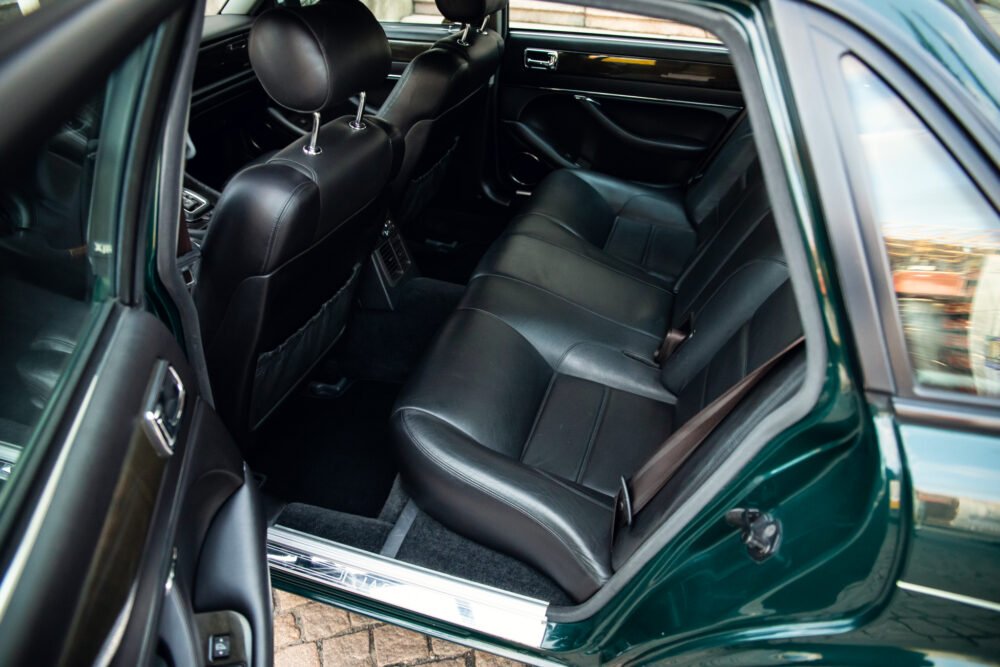 Luxurious black leather car interior, open door view.