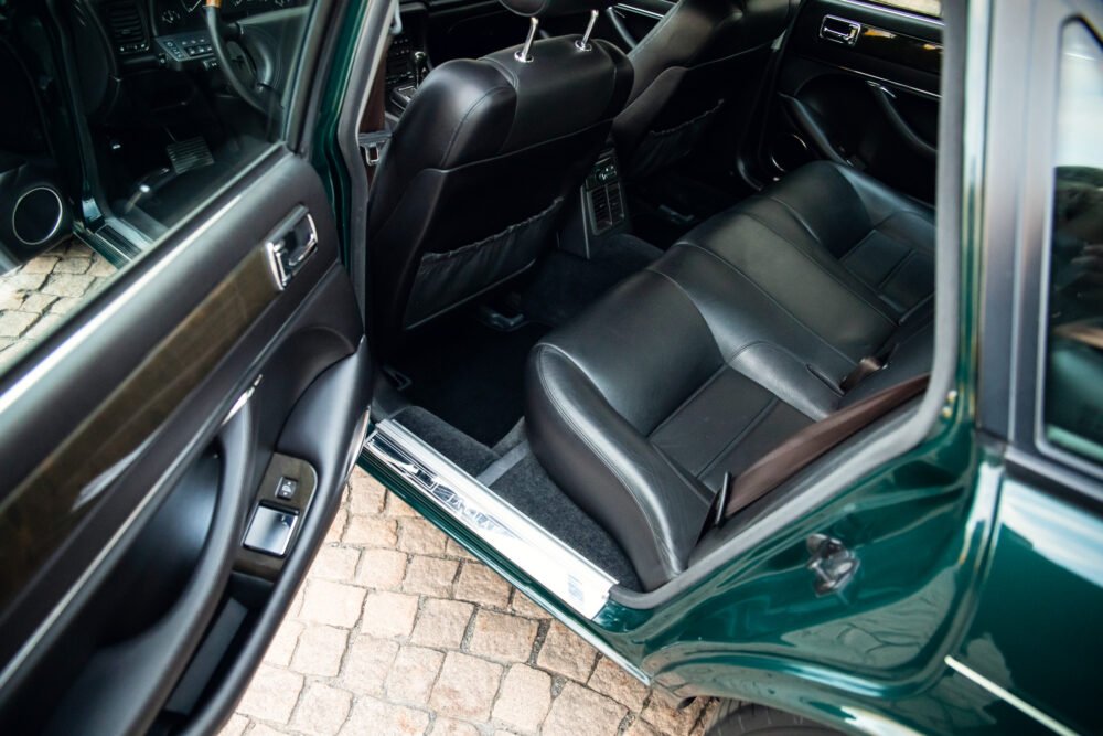 Luxury car interior, open door, black leather seats.
