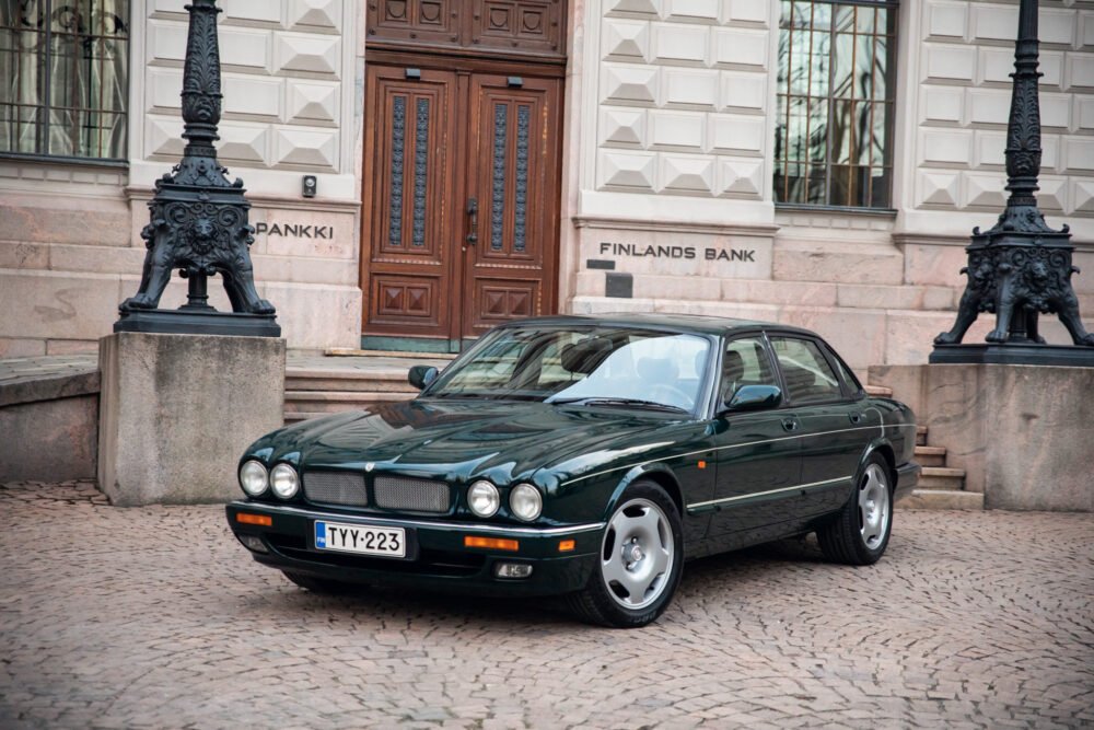 Green Jaguar sedan parked in front of Finland's Bank.
