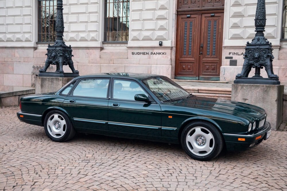 Green Jaguar car parked in front of Suomen Pankki building.