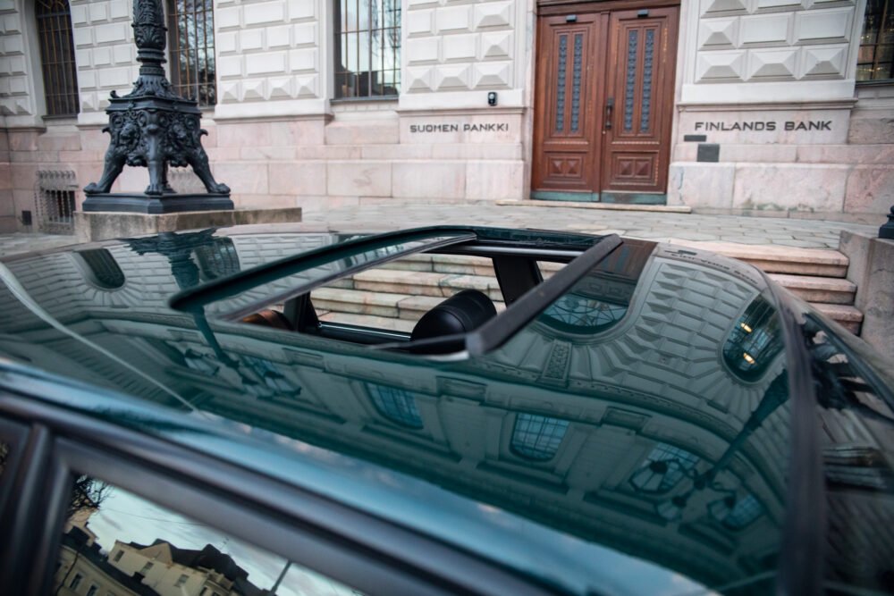 Luxury car reflects Finland's Bank architecture in Helsinki.