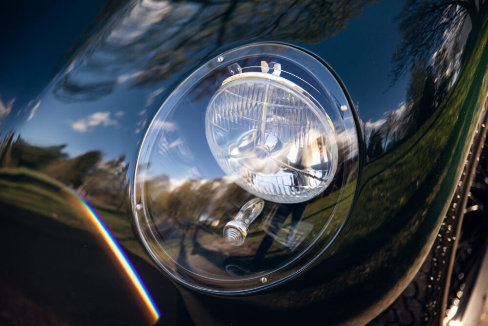 Close-up of vintage car headlight and reflections.