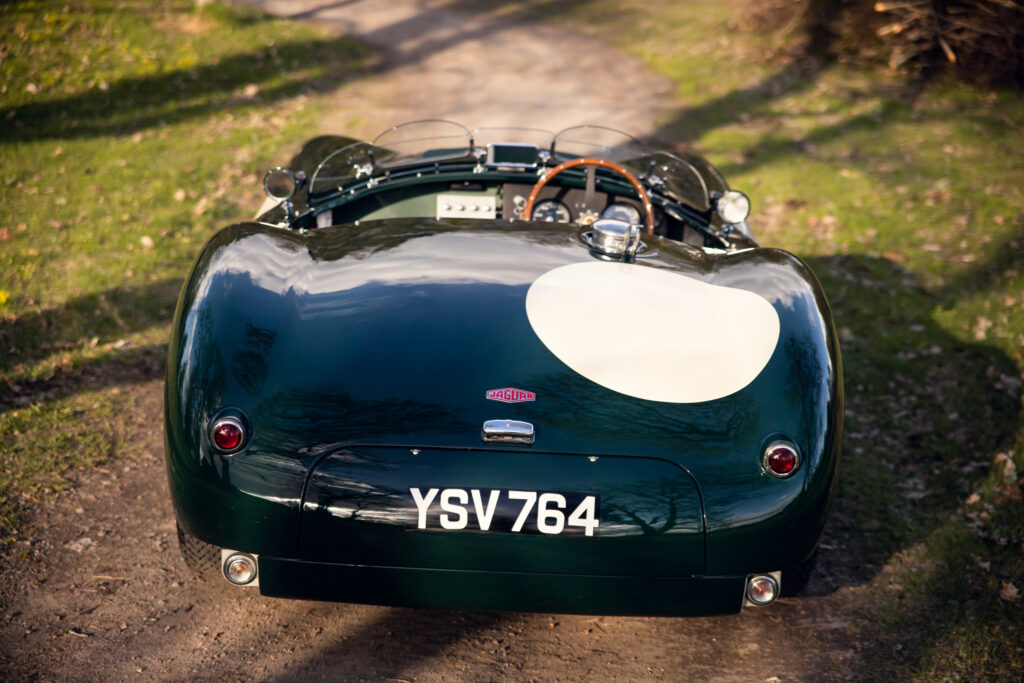Vintage Jaguar sports car on a forest road.