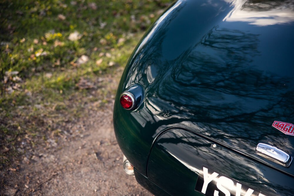 Green vintage car, close-up on taillight and smooth reflections.