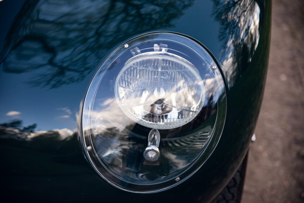 Close-up of vintage car headlight with reflections.