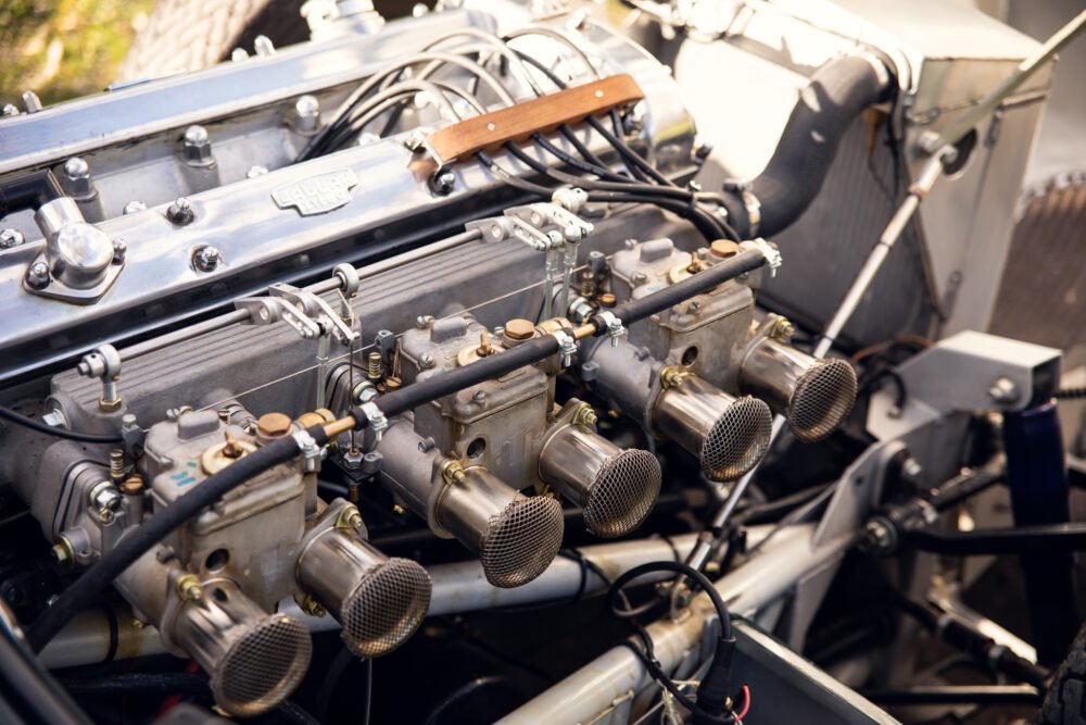 Vintage Jaguar engine showing detailed carburetors and components.