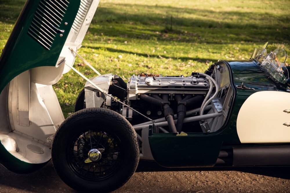 Vintage racing car with exposed engine in park.