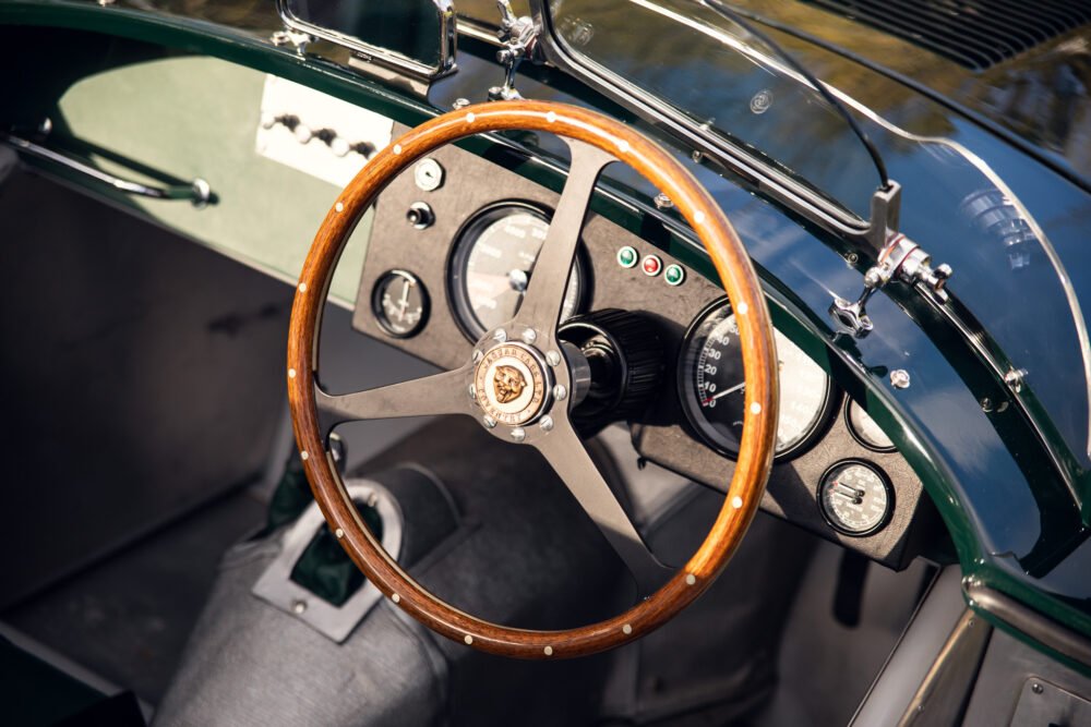 Classic car wooden steering wheel and dashboard detail.