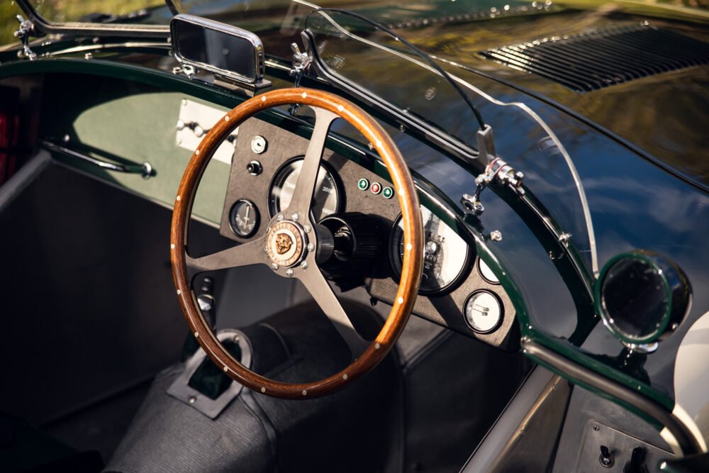 Vintage car interior with wooden steering wheel and dashboard.