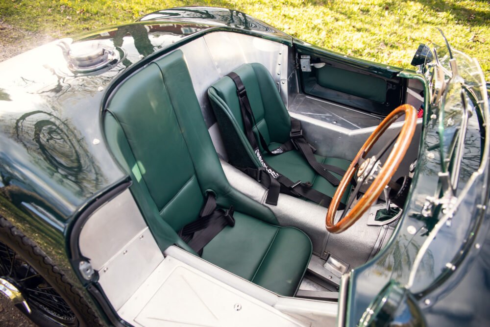 Vintage green car interior with wooden steering wheel.