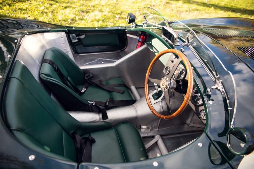 Vintage green convertible car interior with wooden steering wheel.