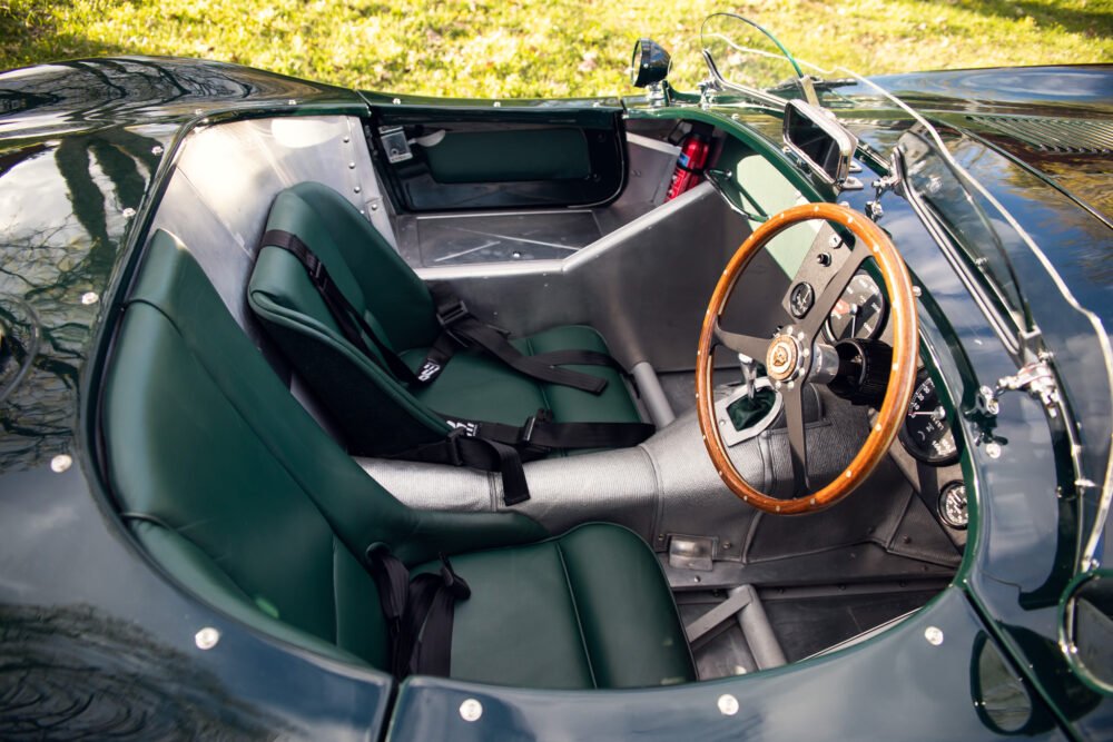 Vintage green roadster's interior with wooden steering wheel.
