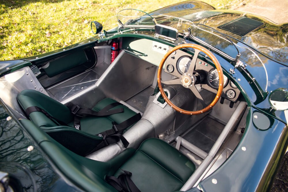 Vintage green roadster interior with wooden steering wheel.