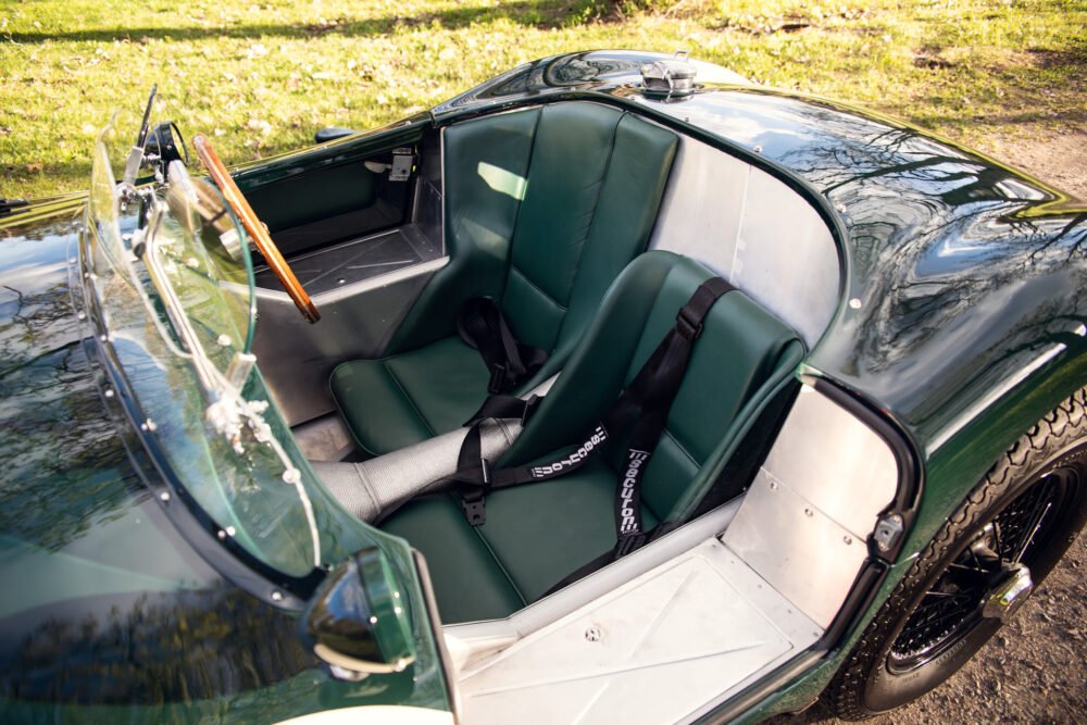 Vintage green sports car with open top and leather seats.