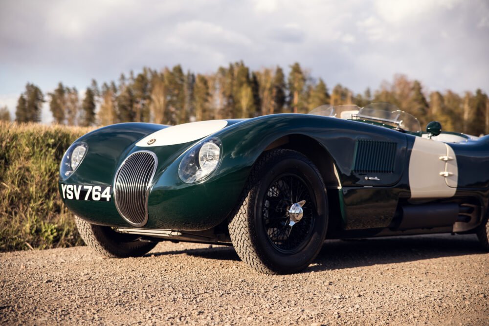 Vintage green Jaguar racing car on country road.