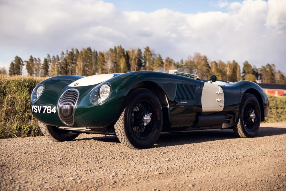Vintage green Jaguar racing car on sunny country road.