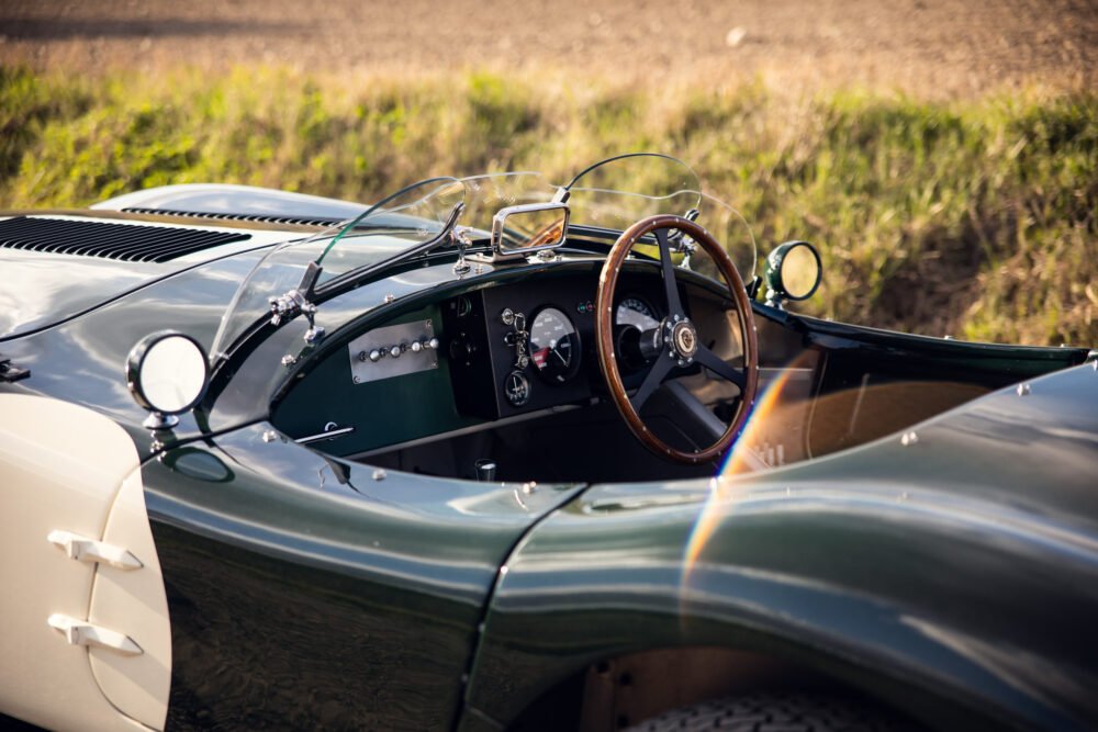 Classic green sports car interior with wooden steering wheel.