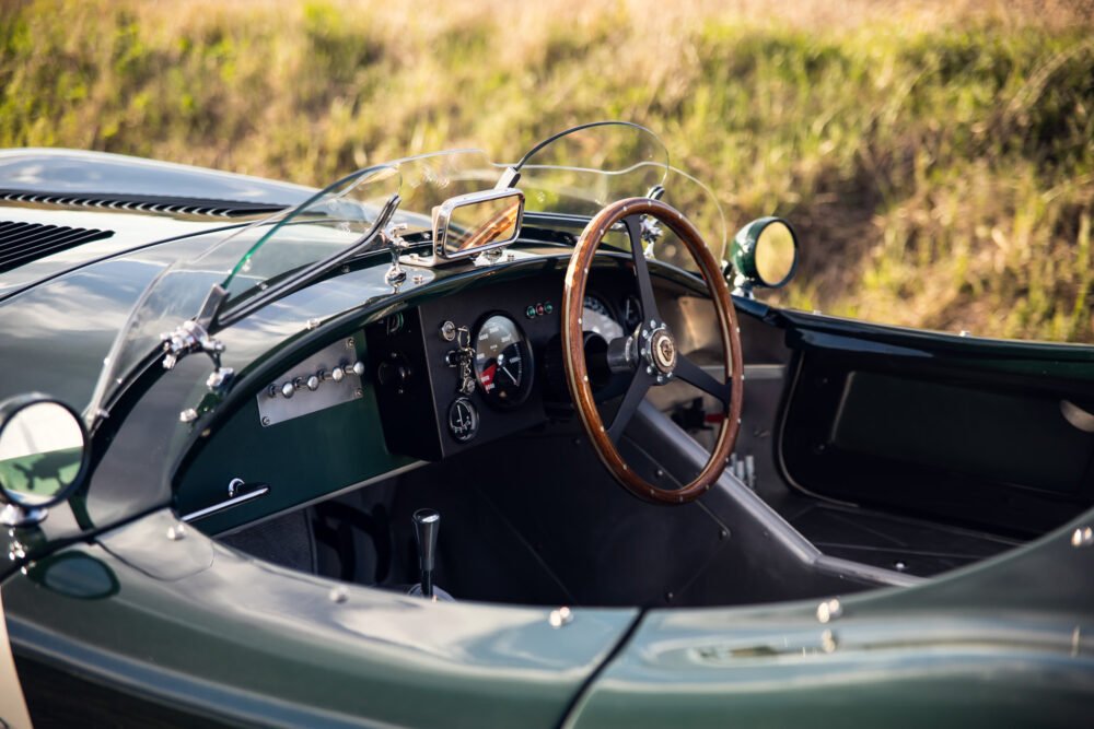 Vintage green sports car interior, wooden steering wheel.