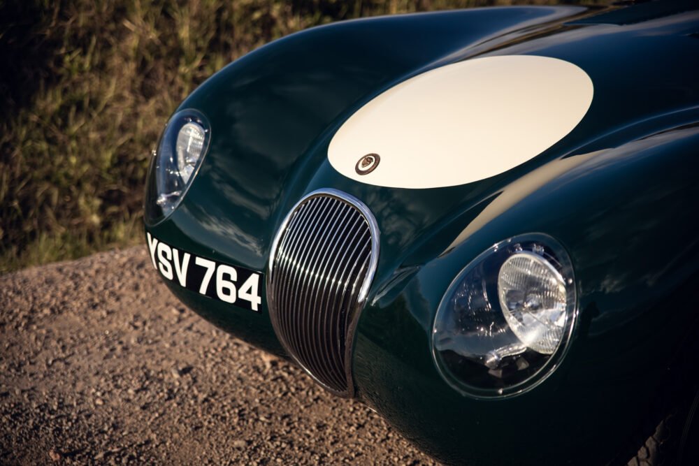 Vintage green sports car close-up with round headlights.