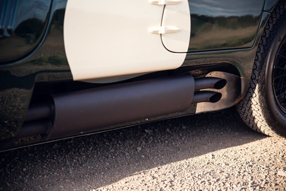 Close-up of car exhaust pipes on gravel road.