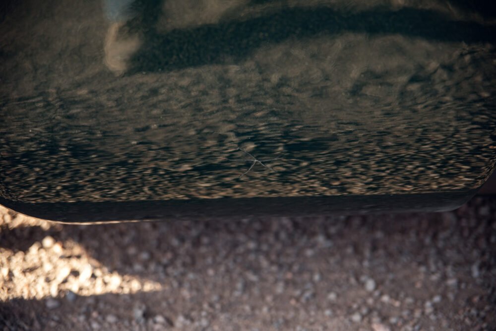 Reflective car bumper with visible scratch.
