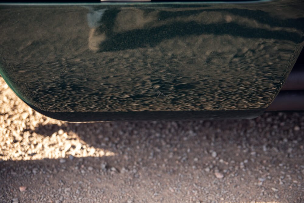 Car's underbody with gravel texture and scratch visible.