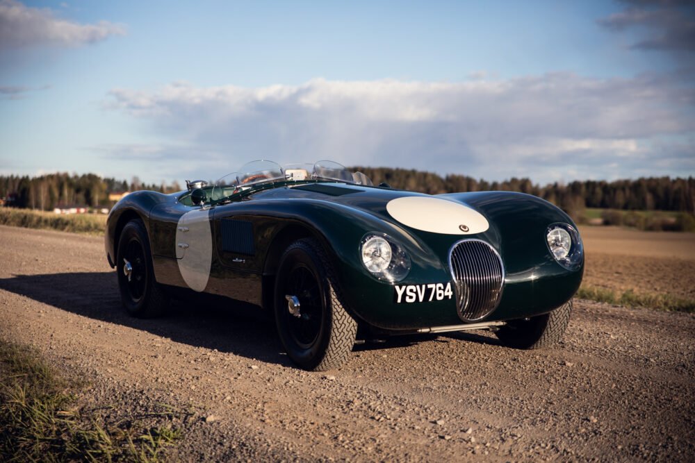 Vintage green Jaguar race car on country road.