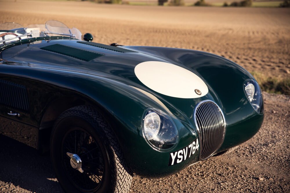 Vintage green Jaguar sports car on country road.