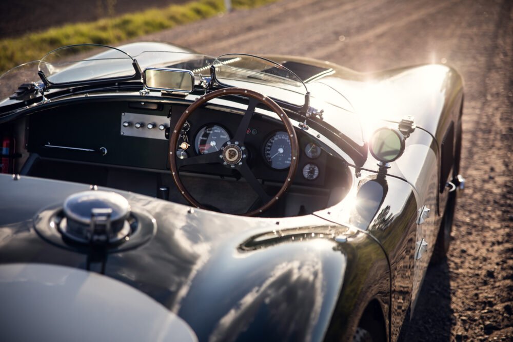 Vintage roadster's dashboard and steering wheel, sunny backdrop.