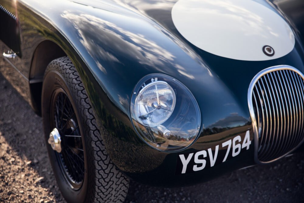 Vintage Jaguar car close-up, focus on headlight and grille.