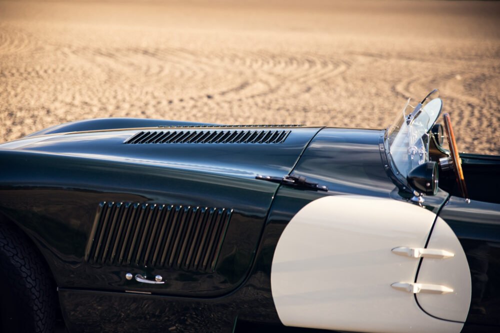 Close-up of vintage convertible car on sandy ground.