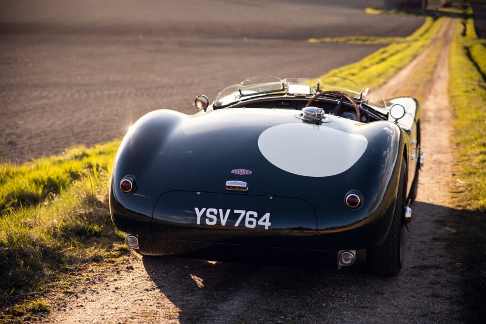 Vintage Jaguar sports car on a countryside road.