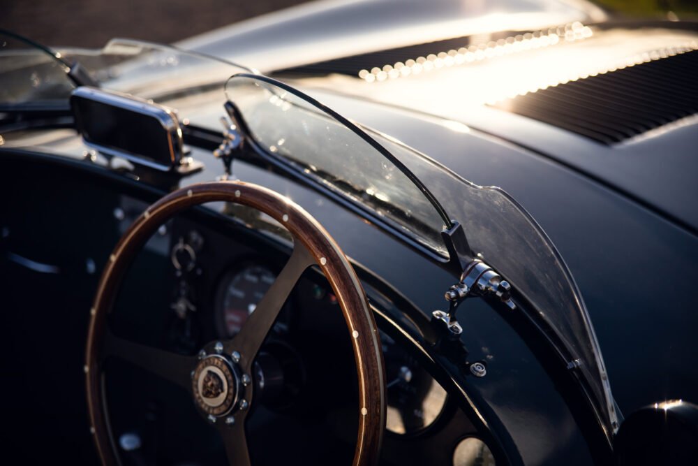 Vintage car dashboard and steering wheel at sunset.