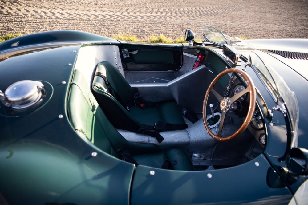 Classic sports car interior, wooden steering wheel, leather seats.