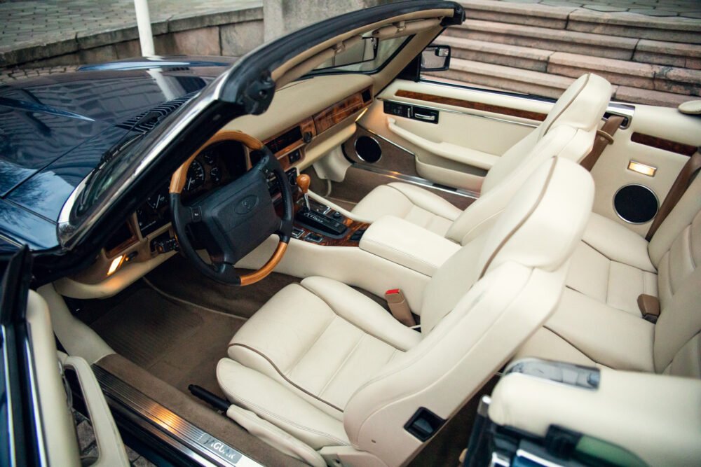 Luxury car interior with beige leather seats and wood dashboard.