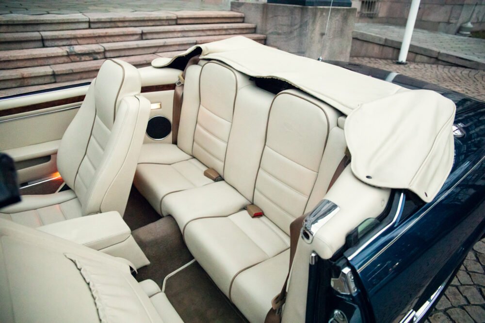 Luxury convertible car interior with cream leather seats.