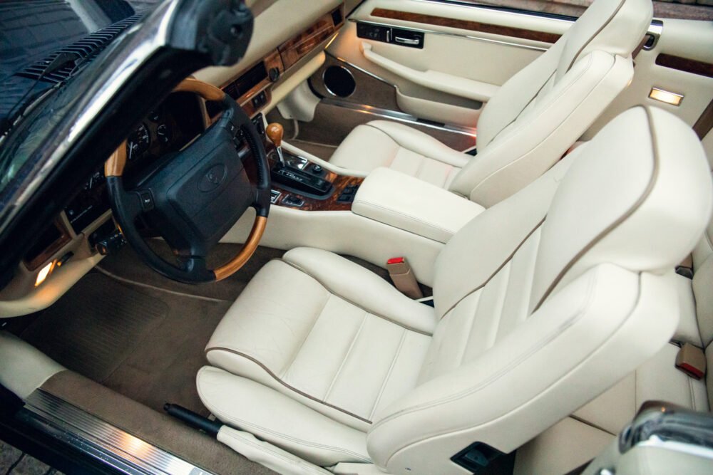 Luxurious car interior with beige leather seats and wood accents.
