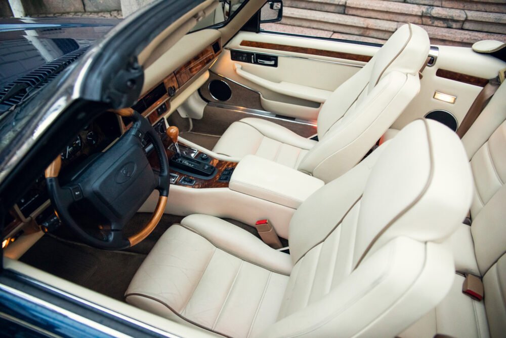 Luxury car interior with cream leather seats and wood trim.