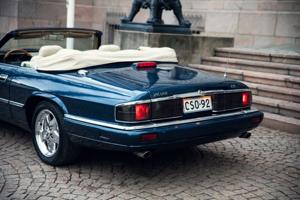 Blue Jaguar XJS convertible near historic statue.