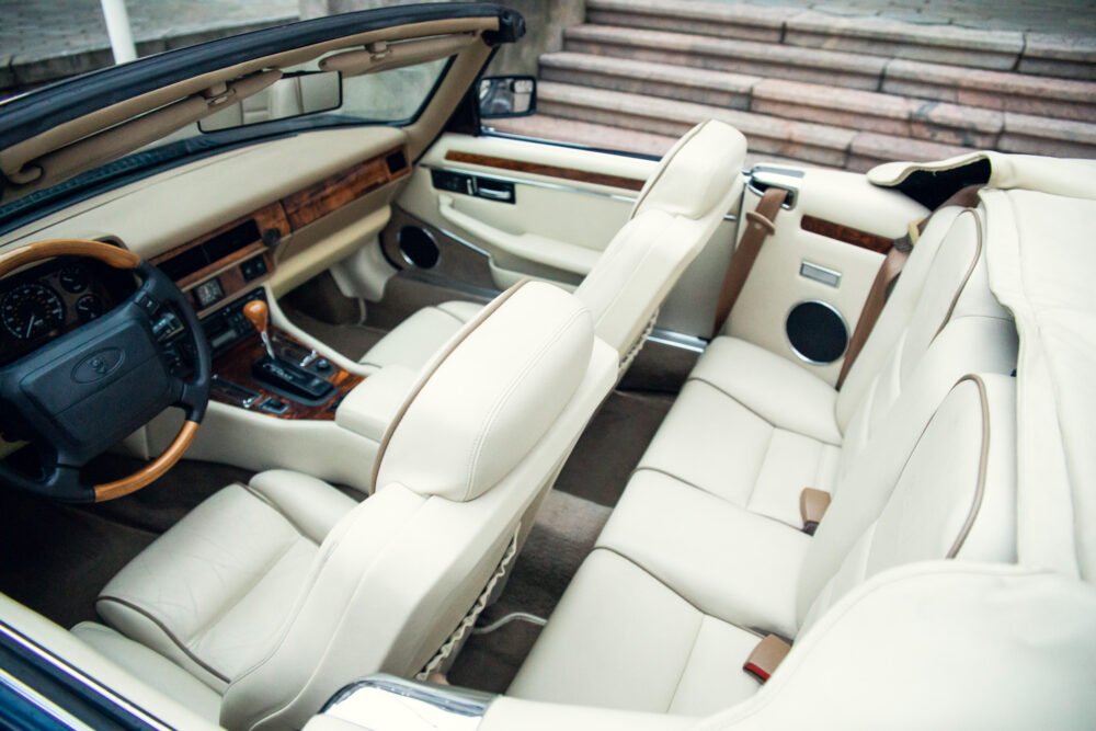 Luxury car interior with beige leather seats and wood trim.