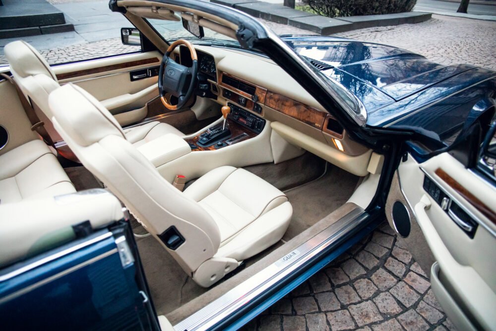 Luxury car interior with open doors and leather seats.